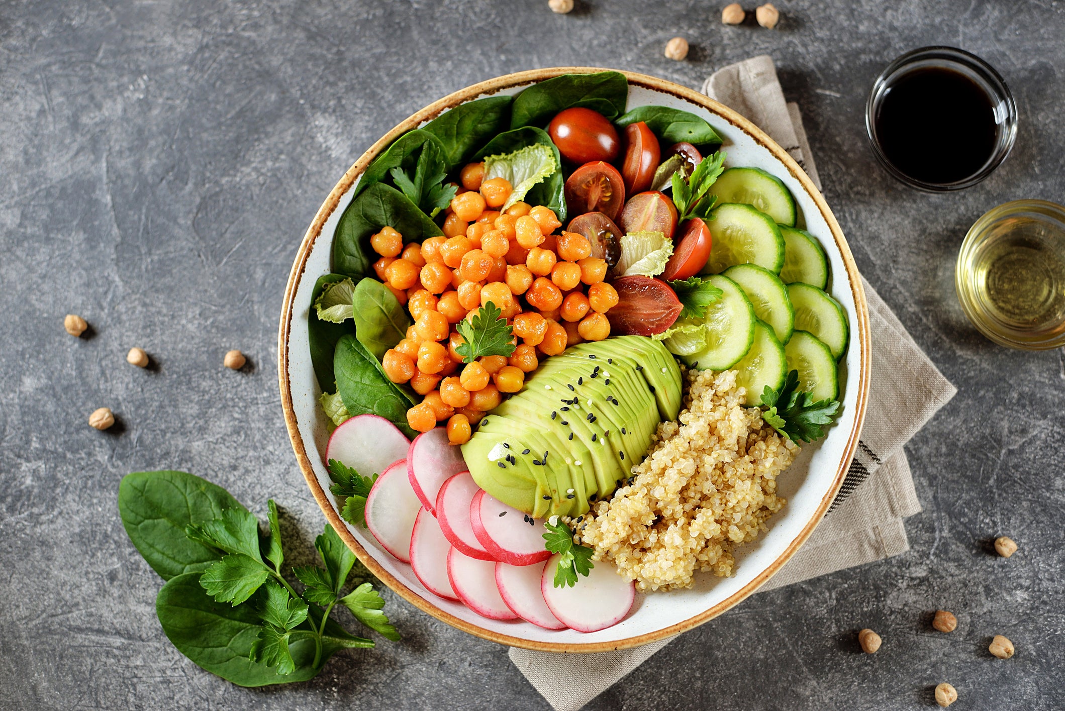 Healthy vegetarian salad with chickpeas, quinoa, cherry tomatoes, cucumber, radish, spinach, avocado and parsley. Ketogenic diet. Top view.