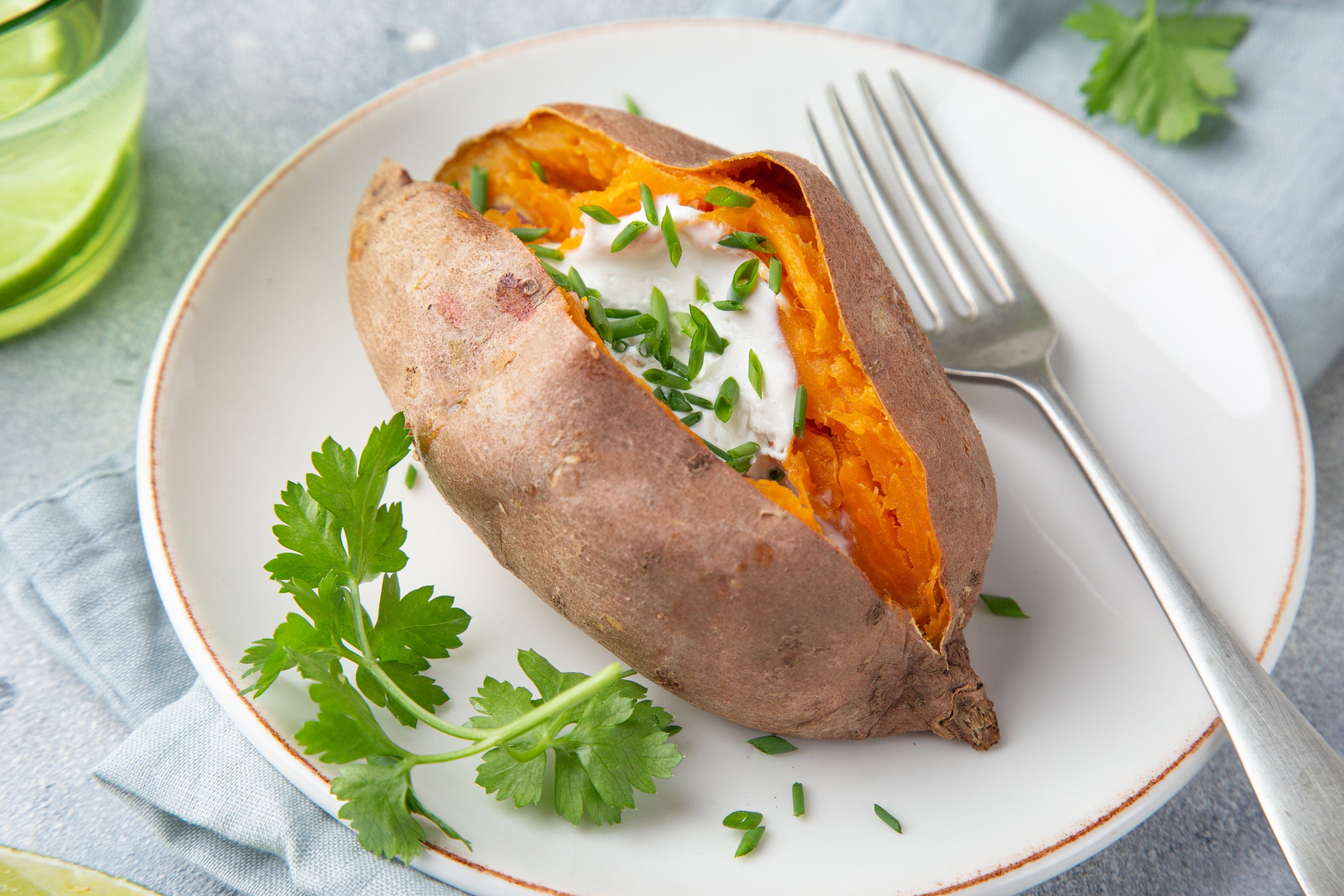 baked sweet potato with yogurt sausce on white plate