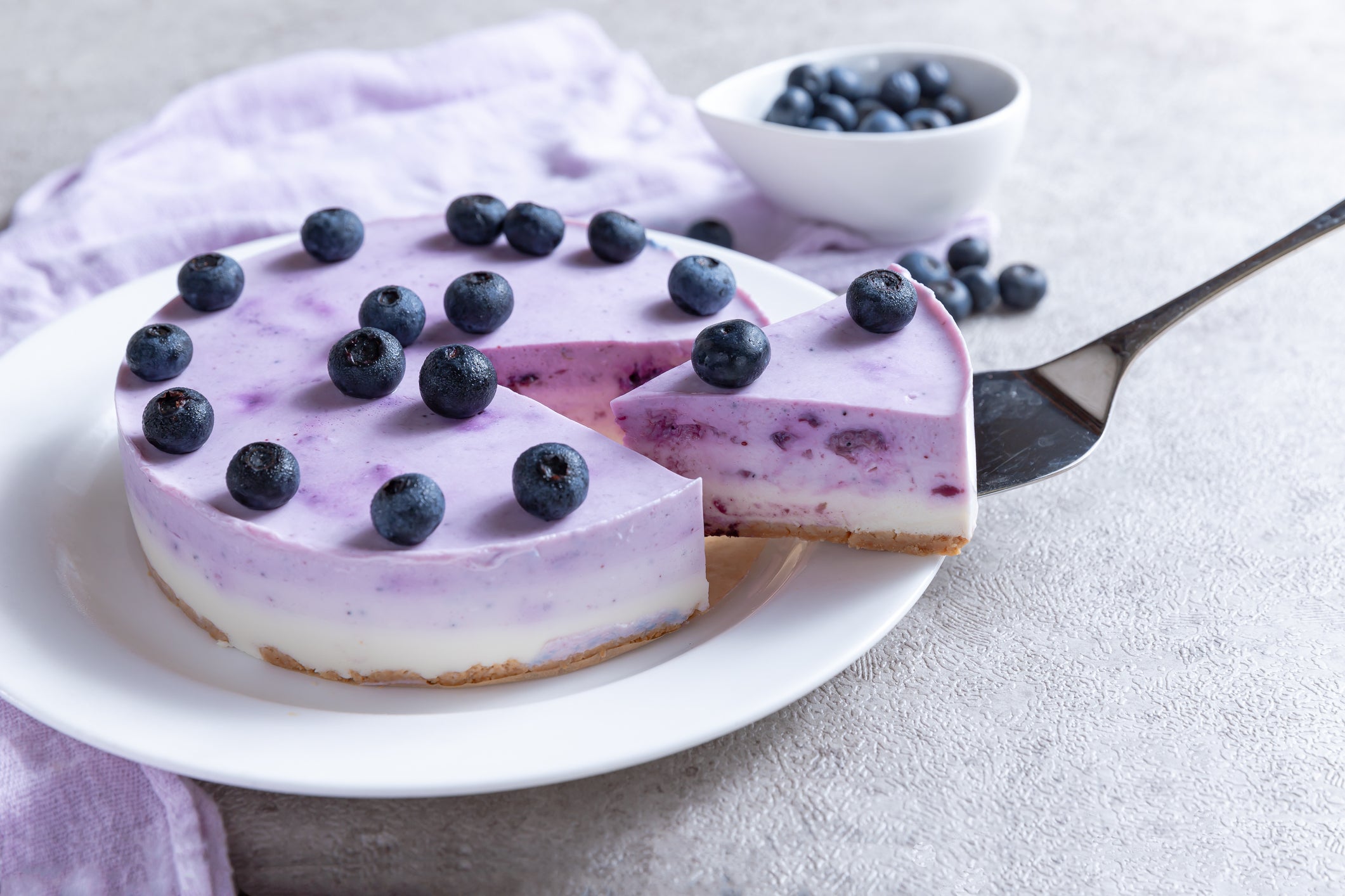 Vanilla blueberry cheesecake decorated with fresh berries on a gray table