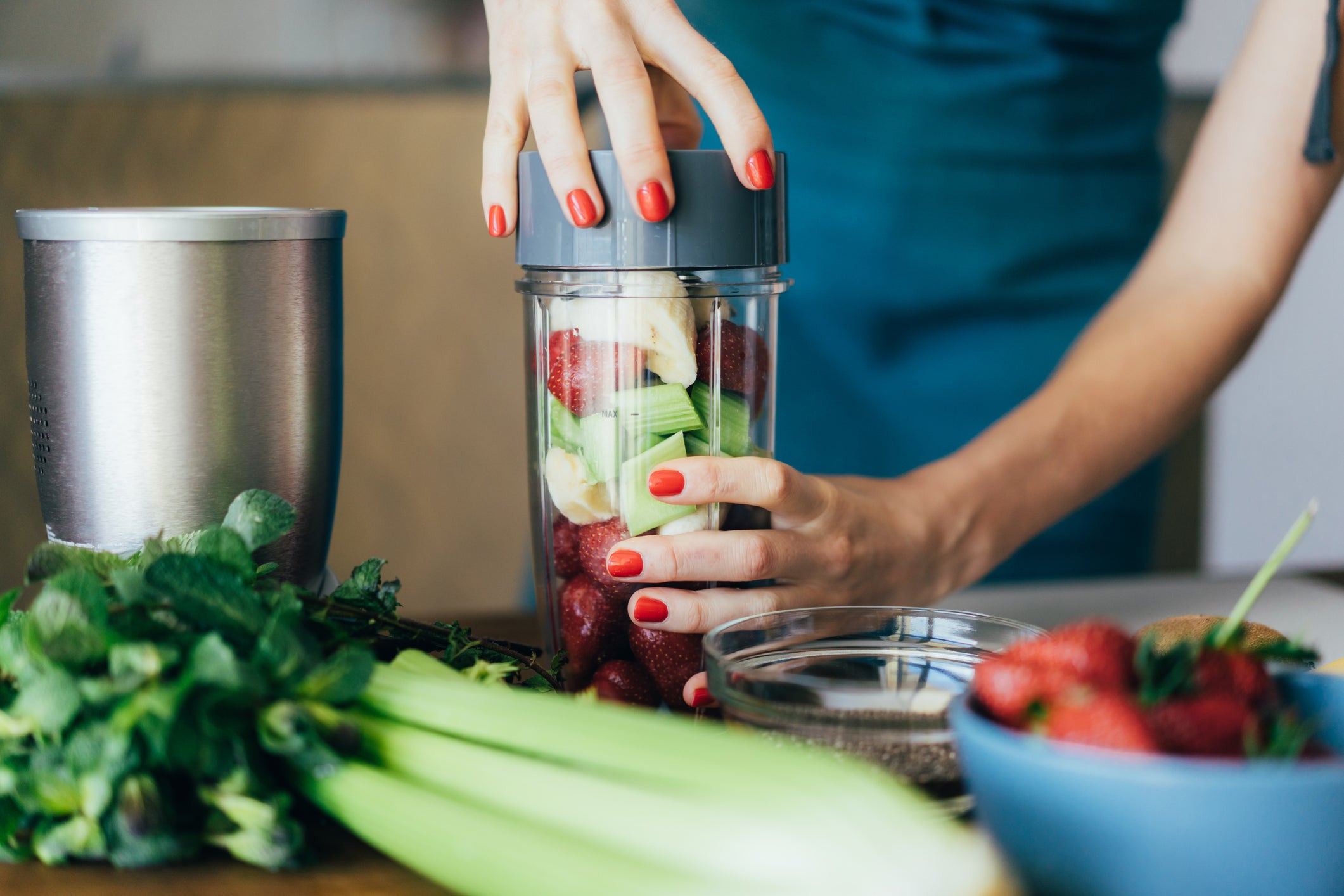 Female hands close the lid of the blender bowl with strawberry, banana and celery. healthy smoothie.