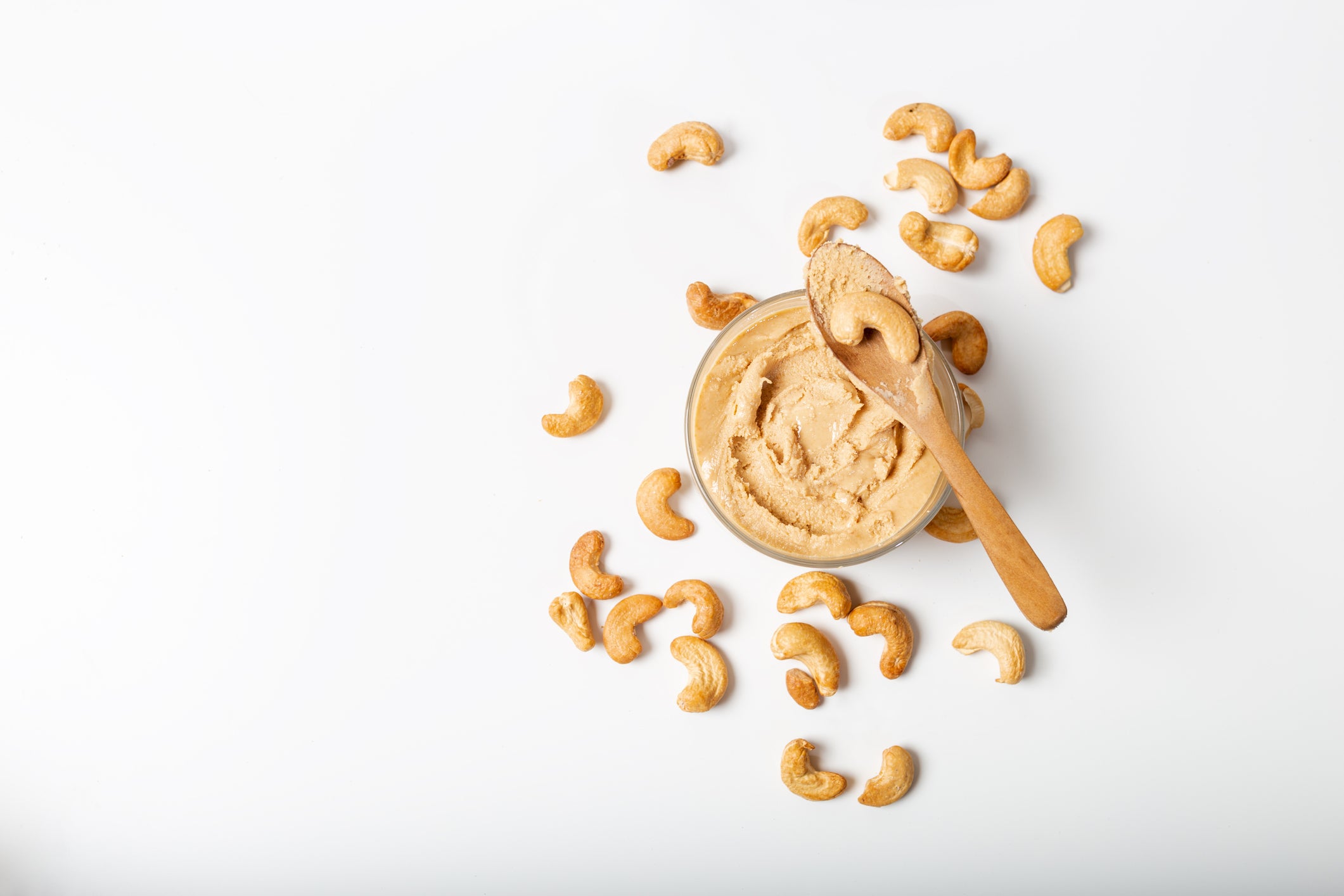 Jar of cashew butter with cashew nuts on the white  background