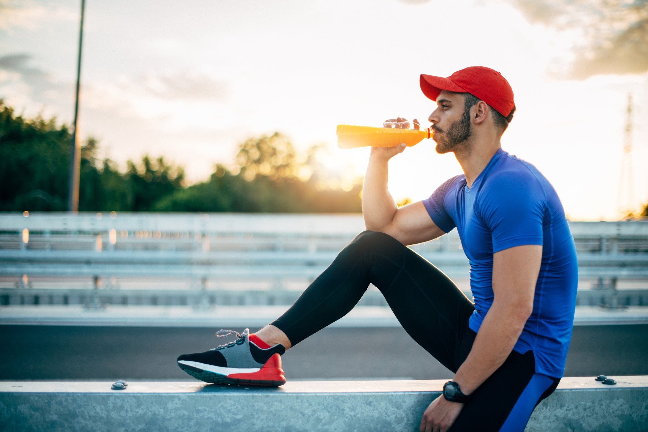 Muscular athlete resting and drinking energy drink