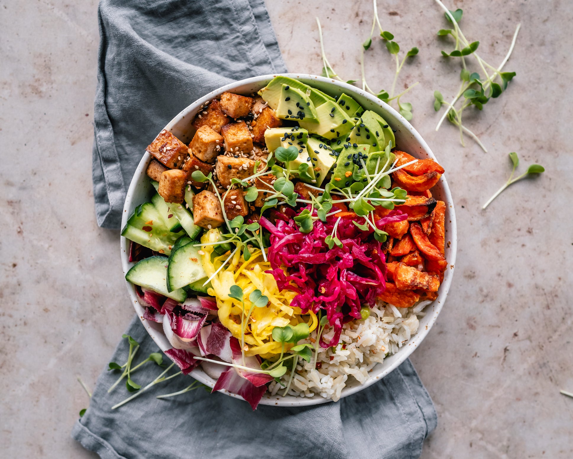 Buddha bowl with pan roasted tofu, avocado, sweet potato, rice, vegetables and mixed seeds