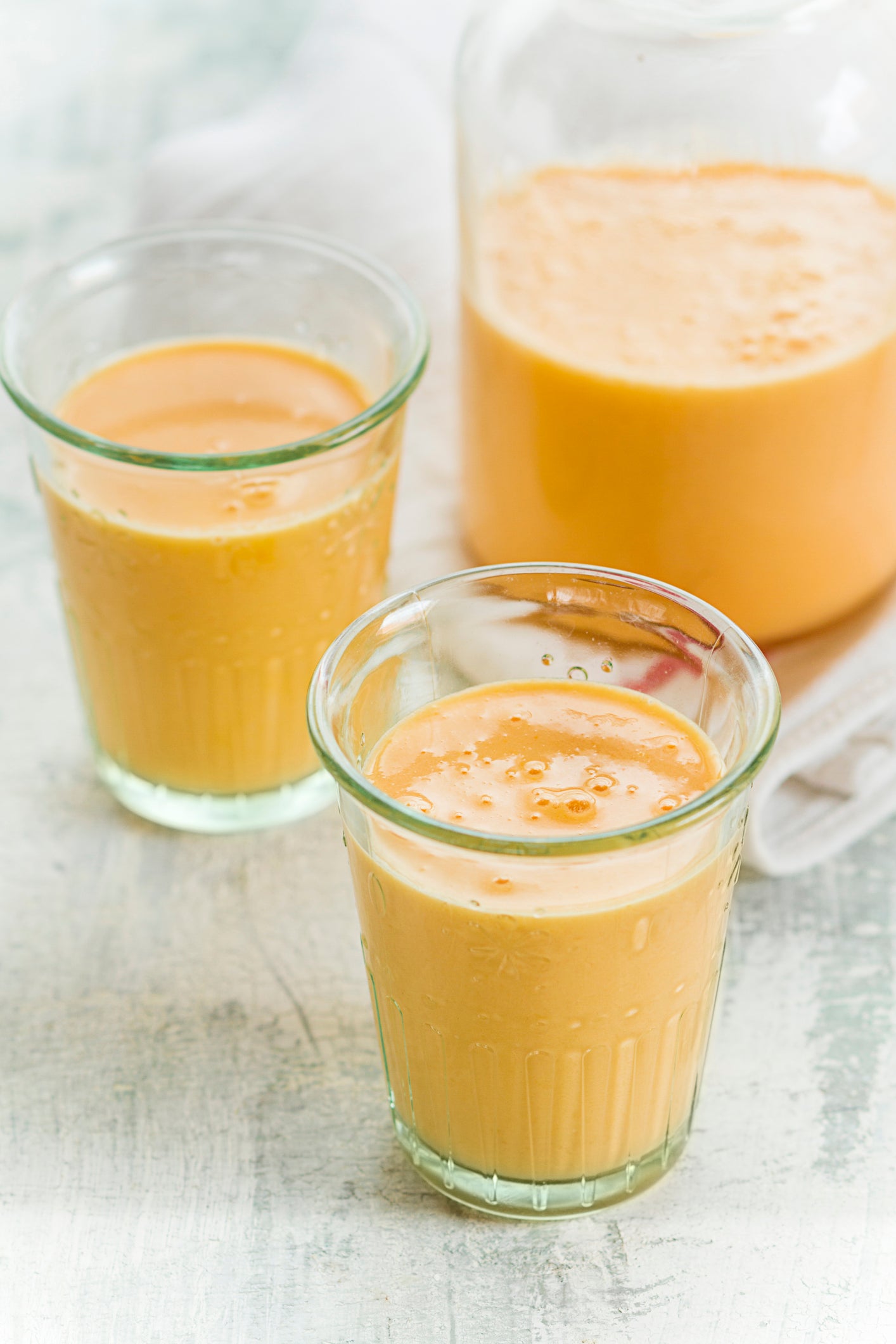 Bottle and two glasses of mango-orange-carrot-smoothie